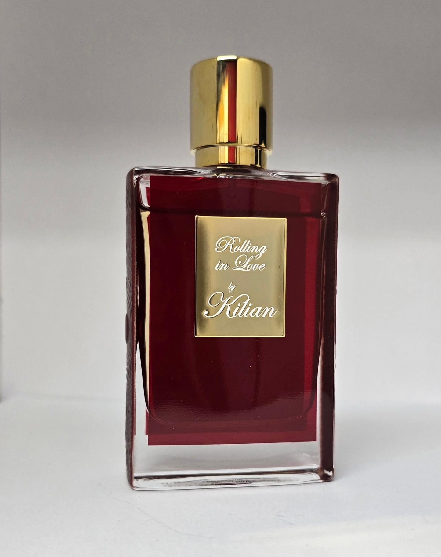 Perfume bottle labeled 'Rolling in Love by Kilian' on a gray background