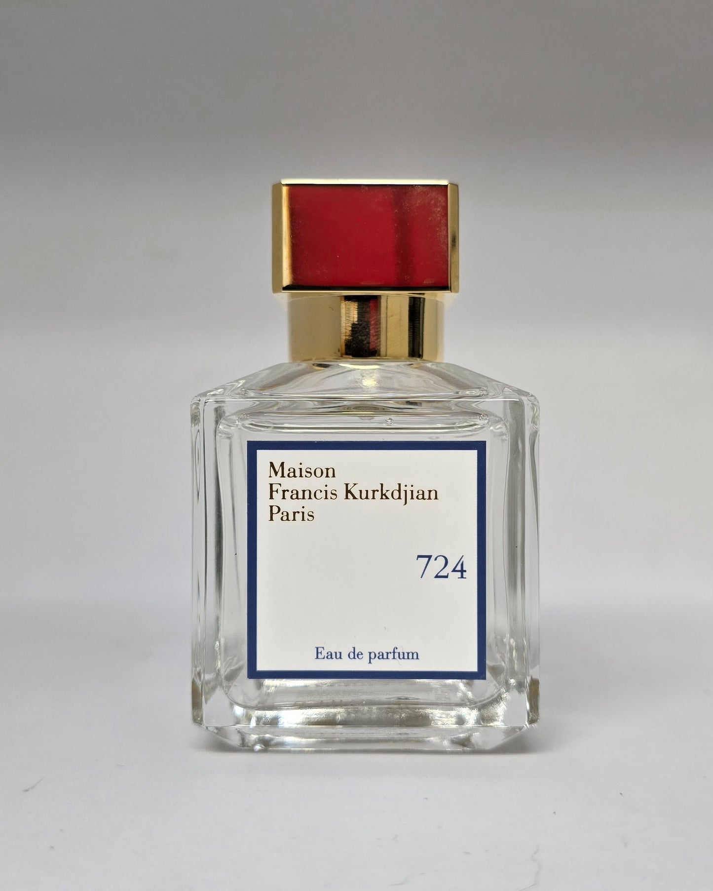 Perfume bottle with gold cap and clear glass body on a gray background