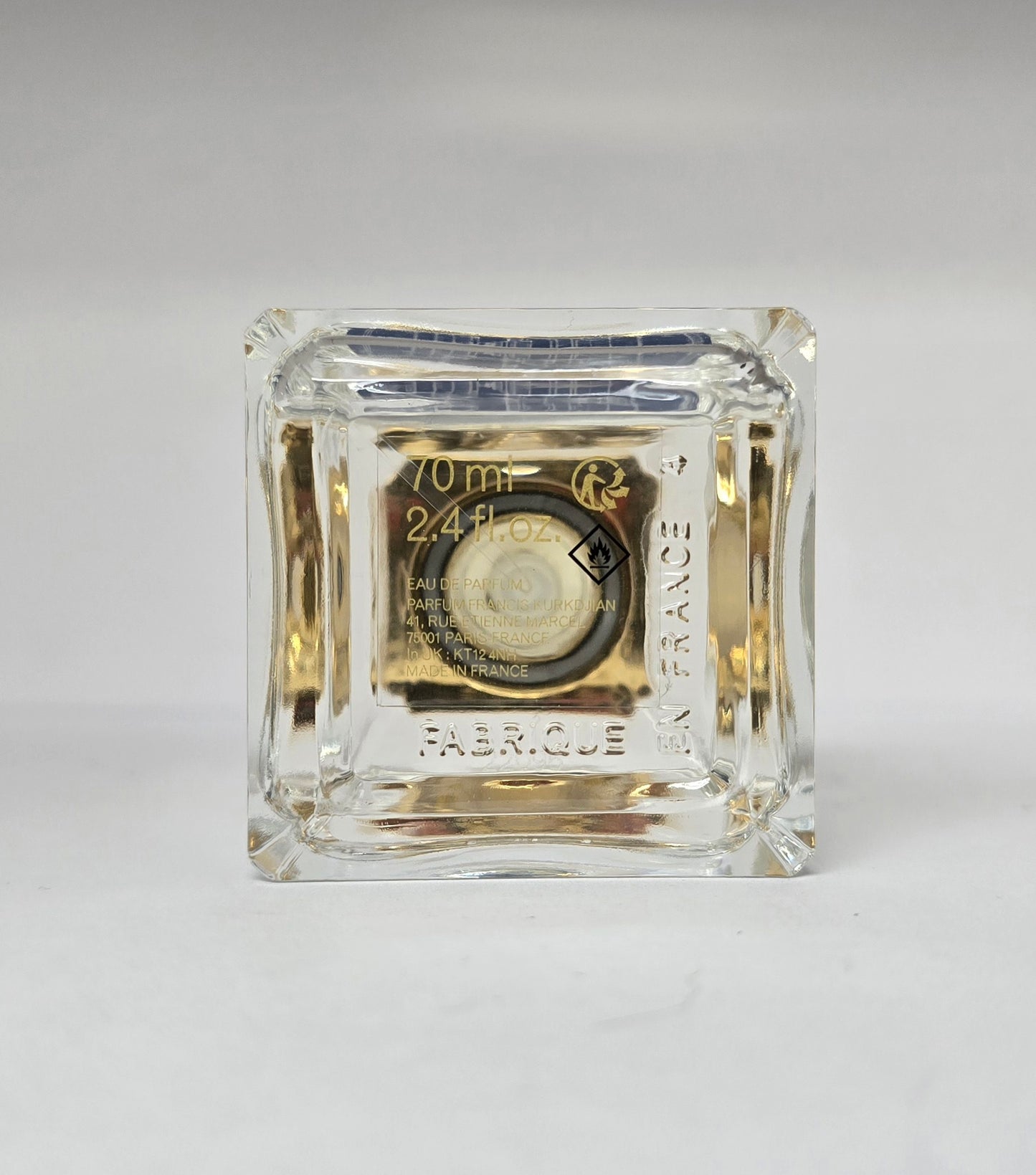 Clear glass perfume bottle with gold label on a white background