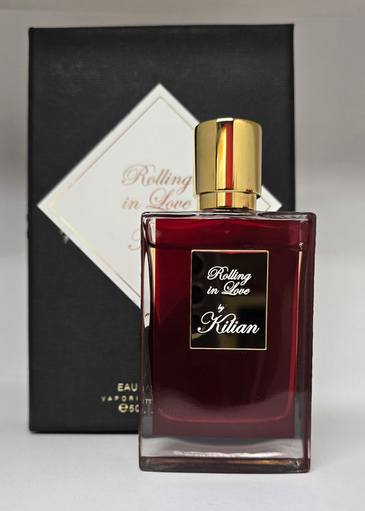 Perfume bottle with gold cap and 'Rolling in Love' by Kilian packaging in the background. 