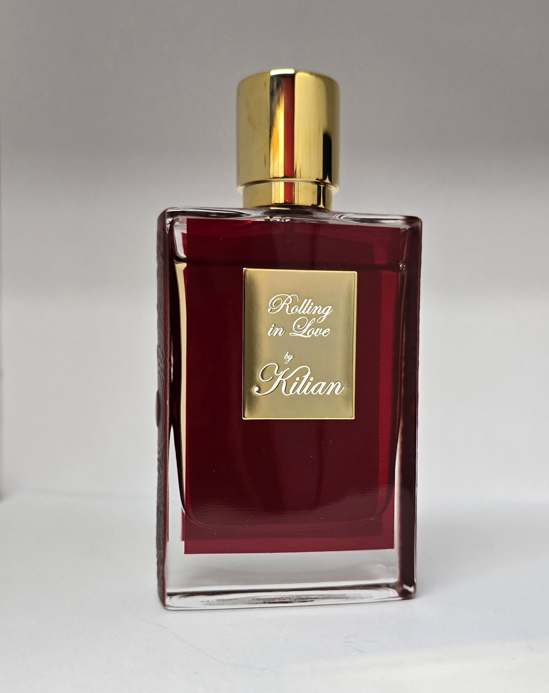 Perfume bottle labeled 'Rolling in Love by Kilian' on a gray background