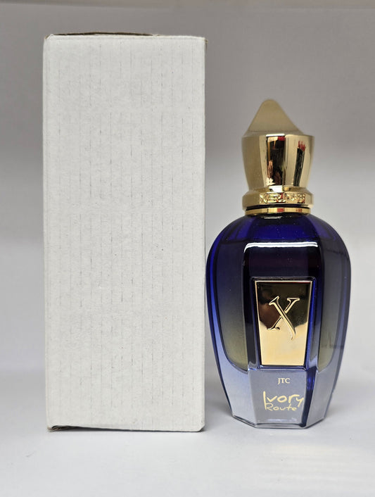 Blue perfume bottle with gold cap and 'X' logo next to a white box on a gray background