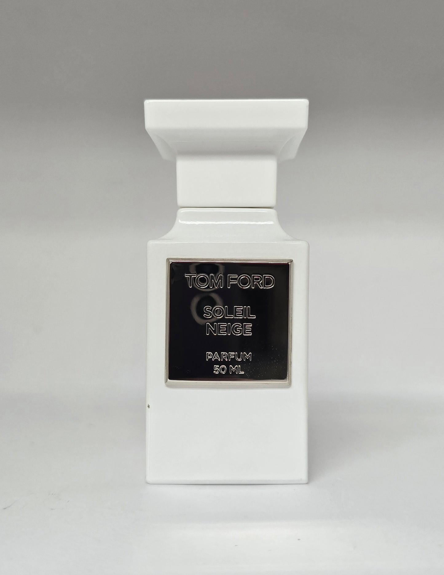 White Tom Ford perfume bottle with black label on a gray background